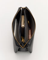 Open handbag with items including a phone, pouch, and lipstick inside.