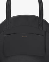 Close-up of a structured handbag with two handles and a pocket.