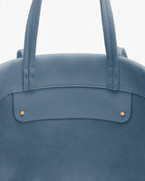 Close-up of a travel bag with two handles and metal studs.