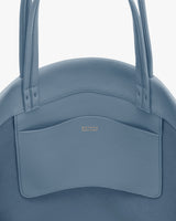 Round bag with two handles and a pocket on the front.