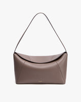 Handbag with a curved flap and a shoulder strap.