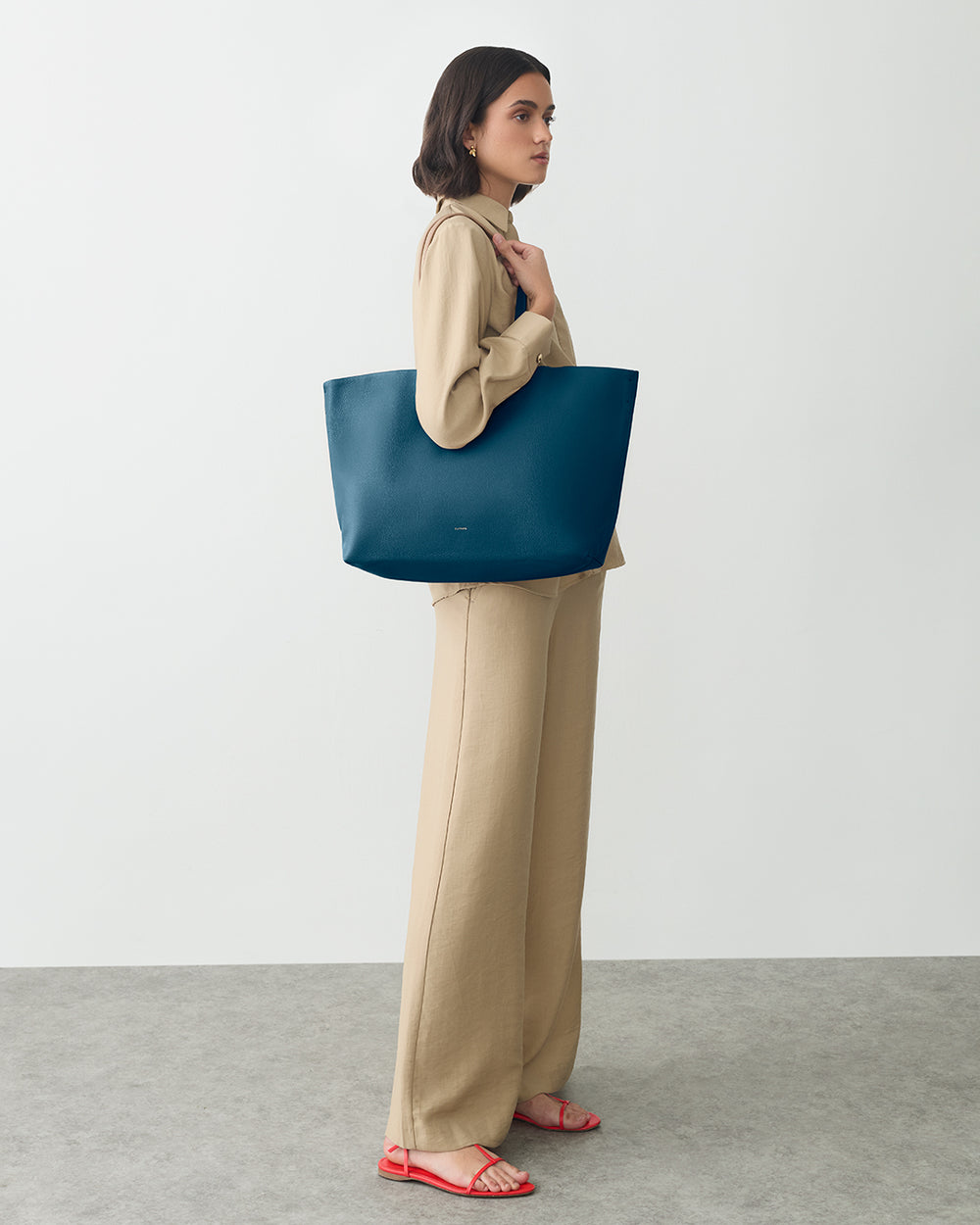 Person standing with large tote bag on shoulder.
