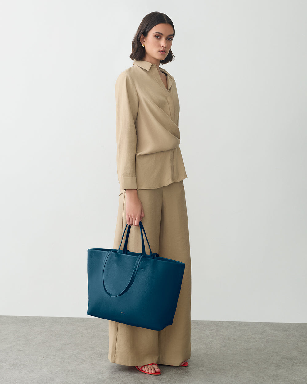 Woman in matching outfit holding a large tote bag.