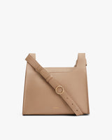 Handbag with a textured finish and adjustable strap, featuring a large front ring.