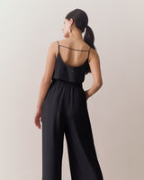 Woman wearing sleeveless top and wide-leg pants, with hand in pocket