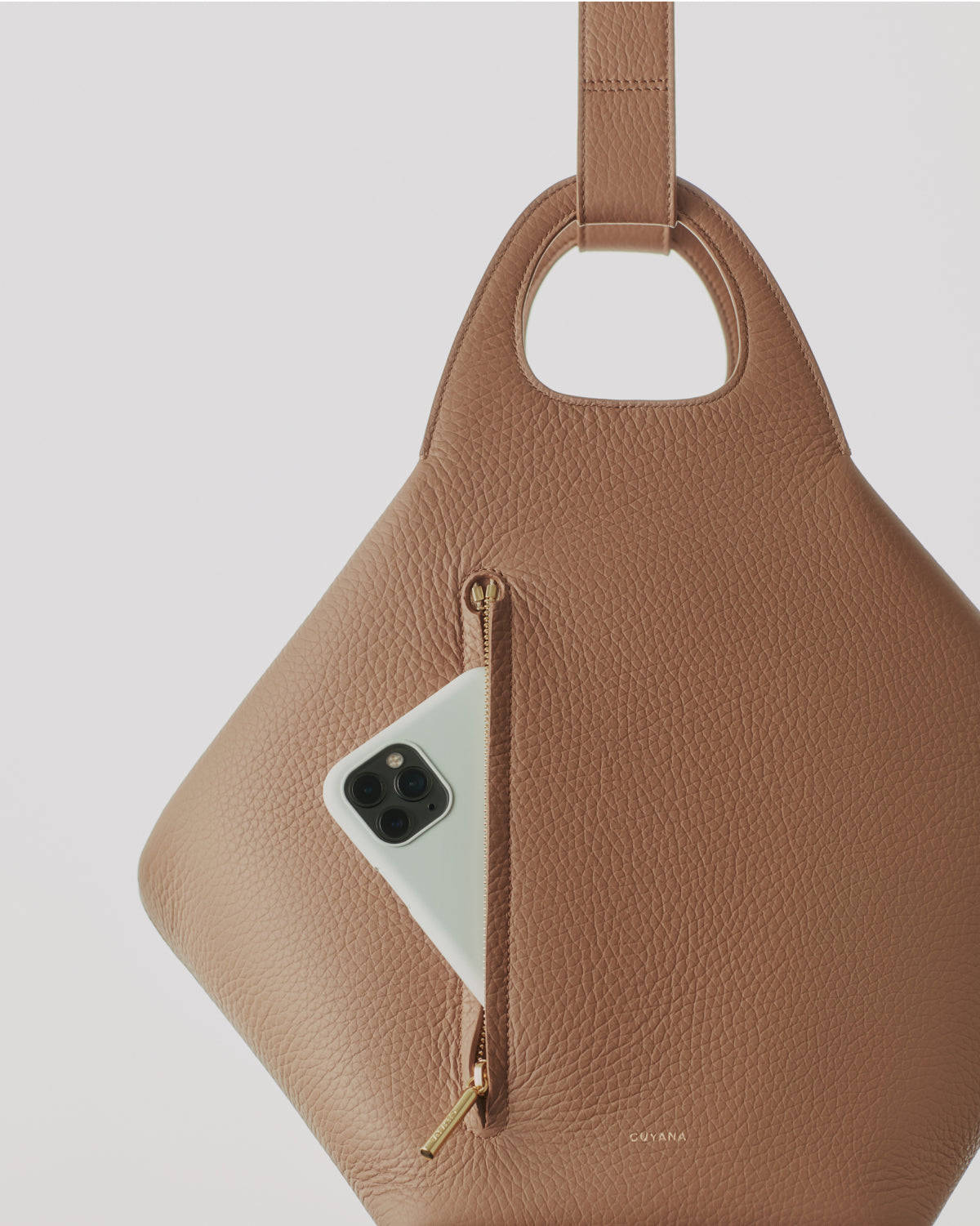 Textured bag with a zipper pocket, holding a smartphone, and a central handle cutout
