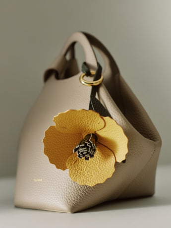 Handbag with large floral decoration attached to the handle.