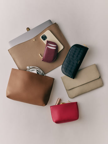 Assorted pouches, clutch and croc-embossed leather wallet with phone, tablet, cables, and lipstick