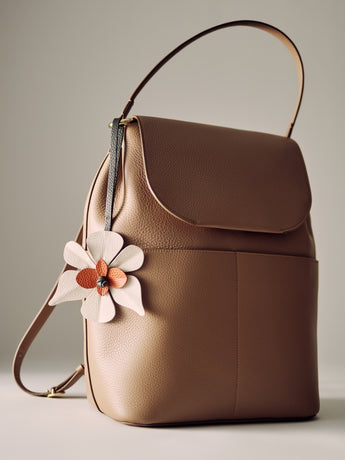 A backpack with a large flower-shaped charm on the side.