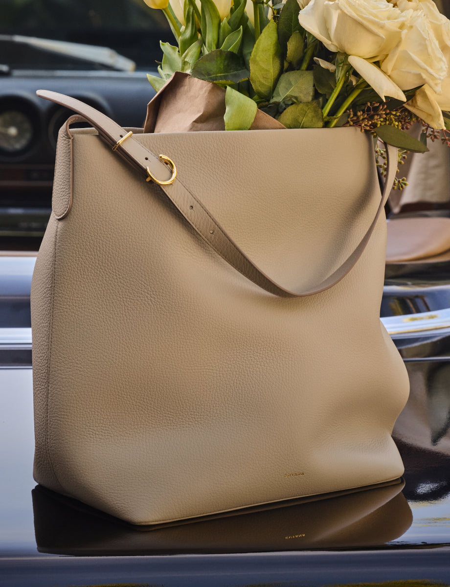 Large handbag with flowers inside placed on car trunk.