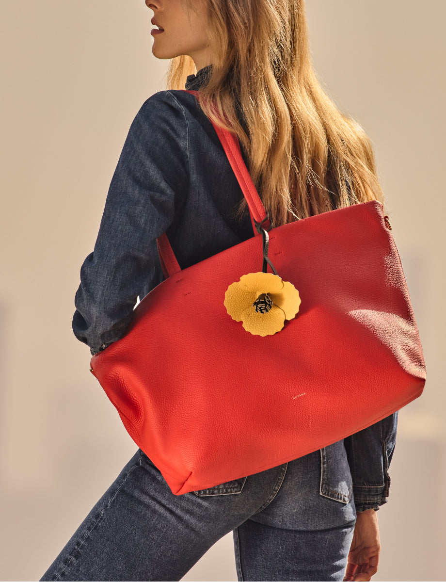 Person carrying large travel bag with flower charm