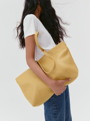 Person holding large tote bag wearing a casual outfit