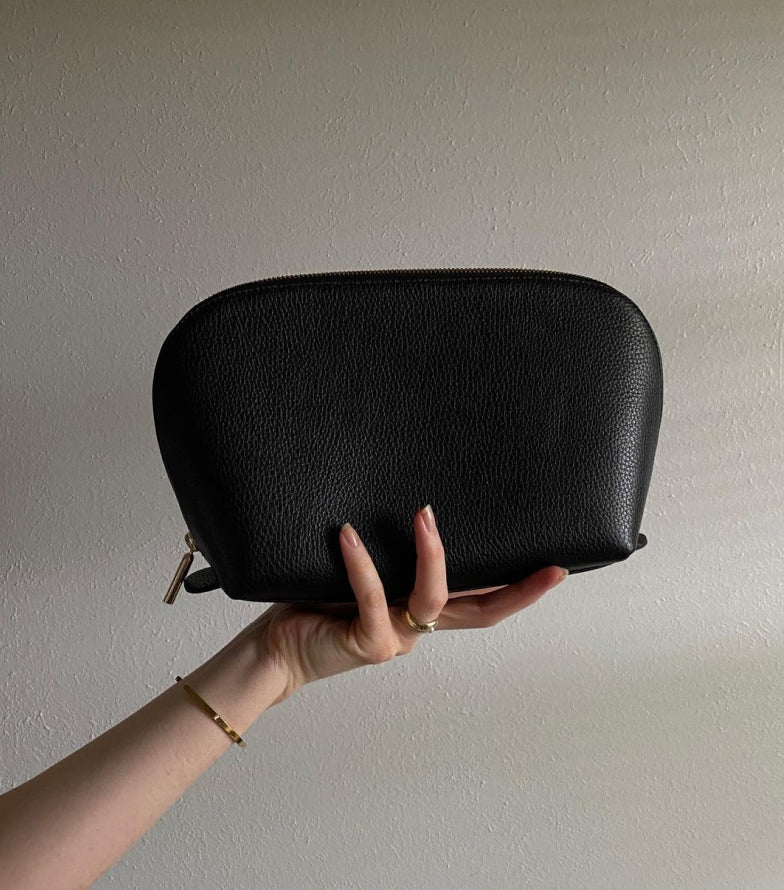 Hand holding a small rectangular case against a plain background.