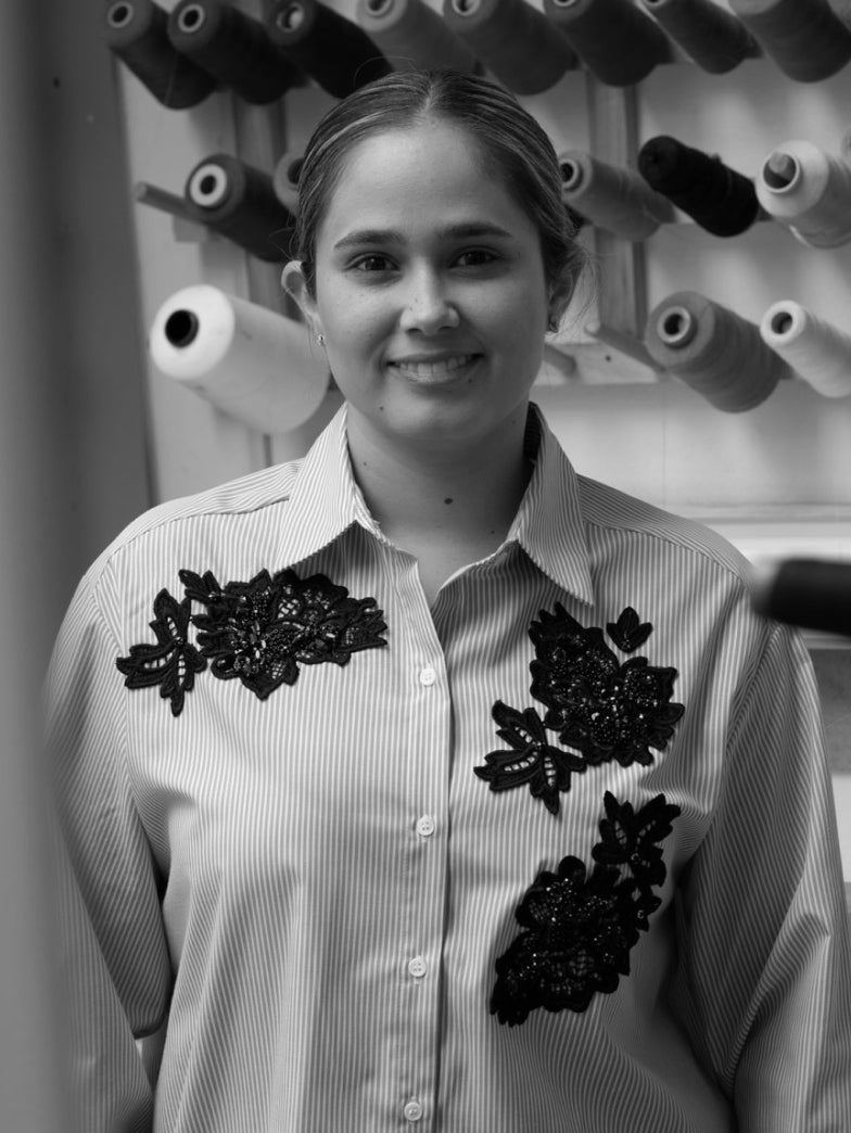 Woman in shirt stands in front of thread spools.