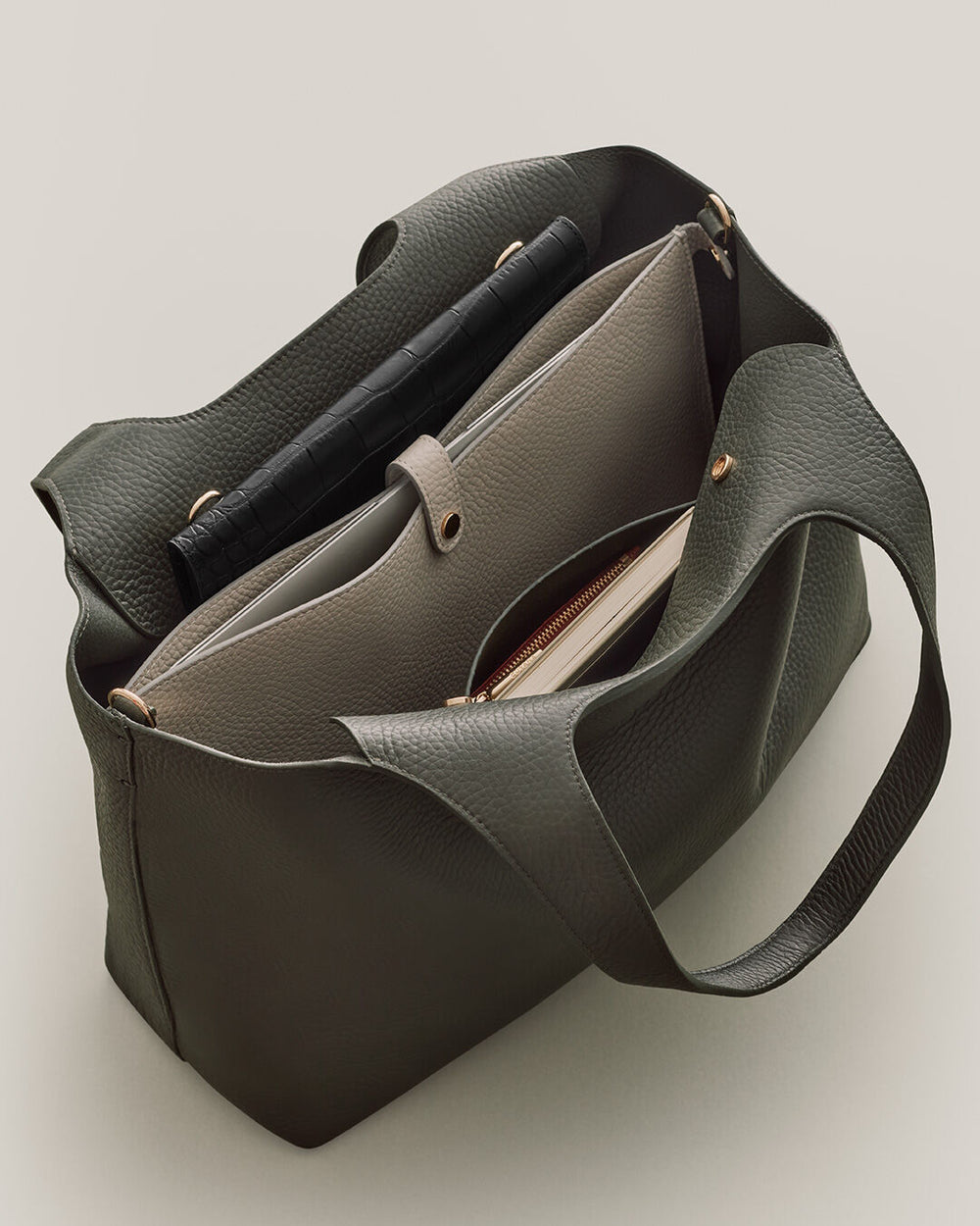 Handbag open with pens and a notebook inside