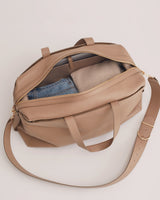 Bag partially unzipped with jeans and a sweater inside.