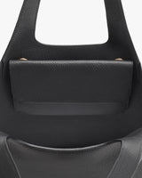 Close-up view of the top part of a handbag with a handle.