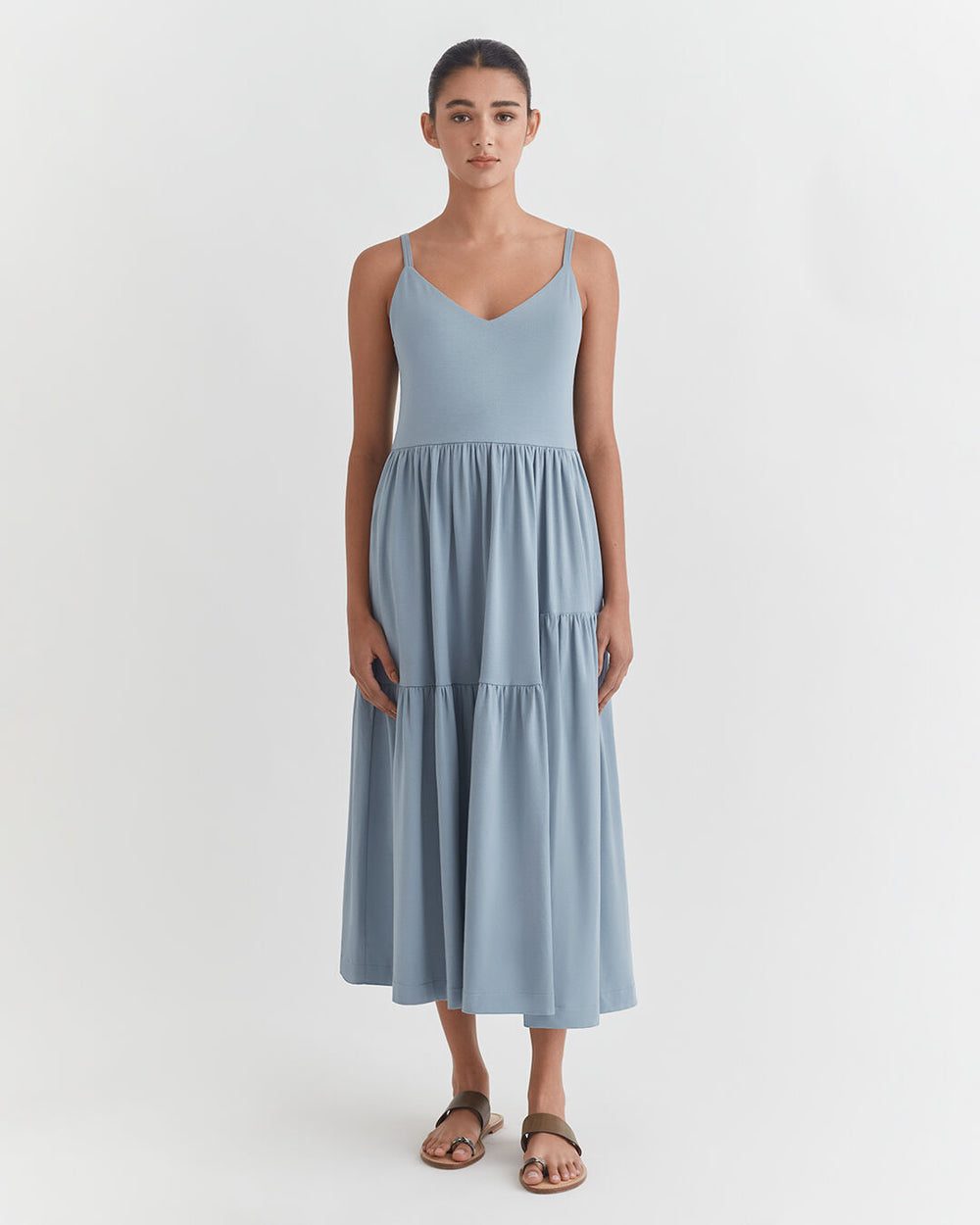 Woman standing in a dress and sandals, facing forward.