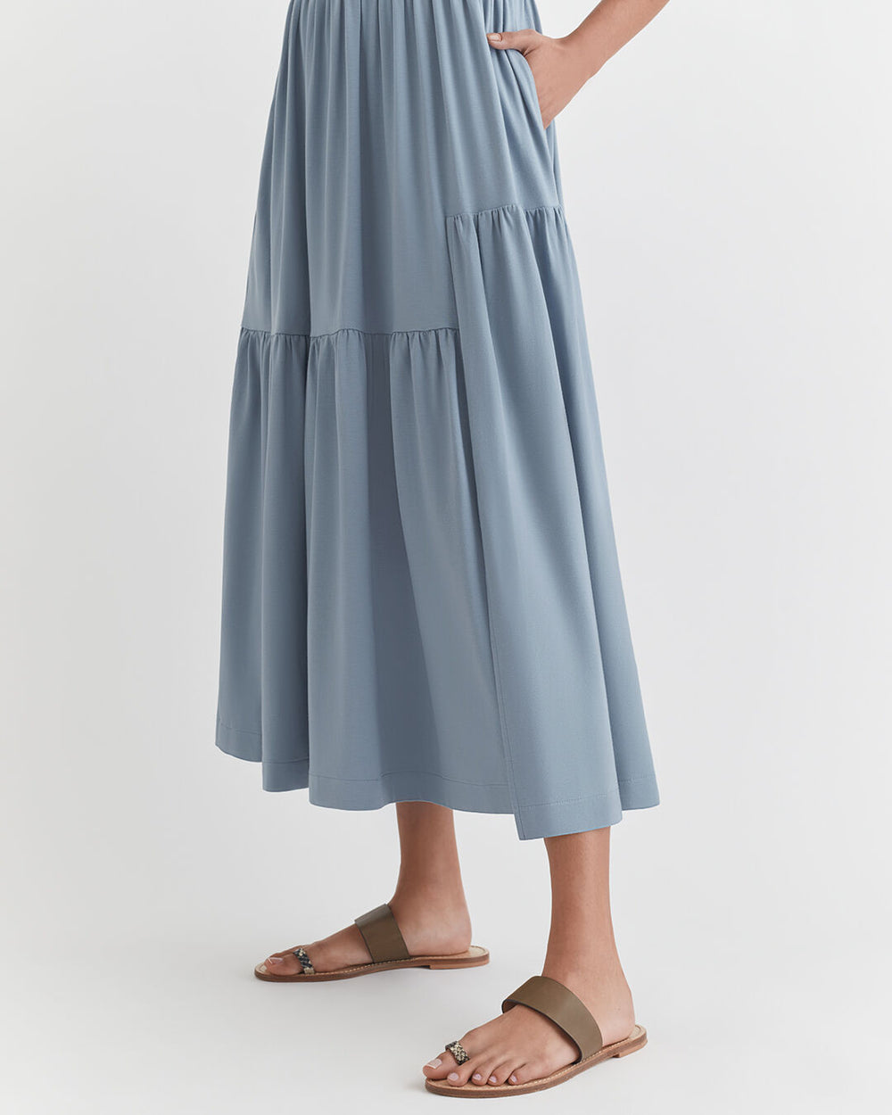 Woman standing in a long dress and sandals.