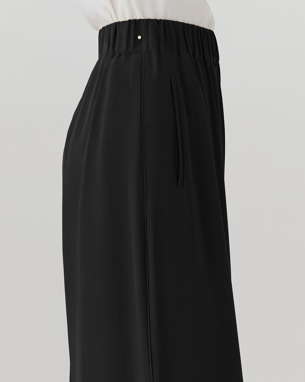 Person wearing long pants with an elastic waistband and side pockets.