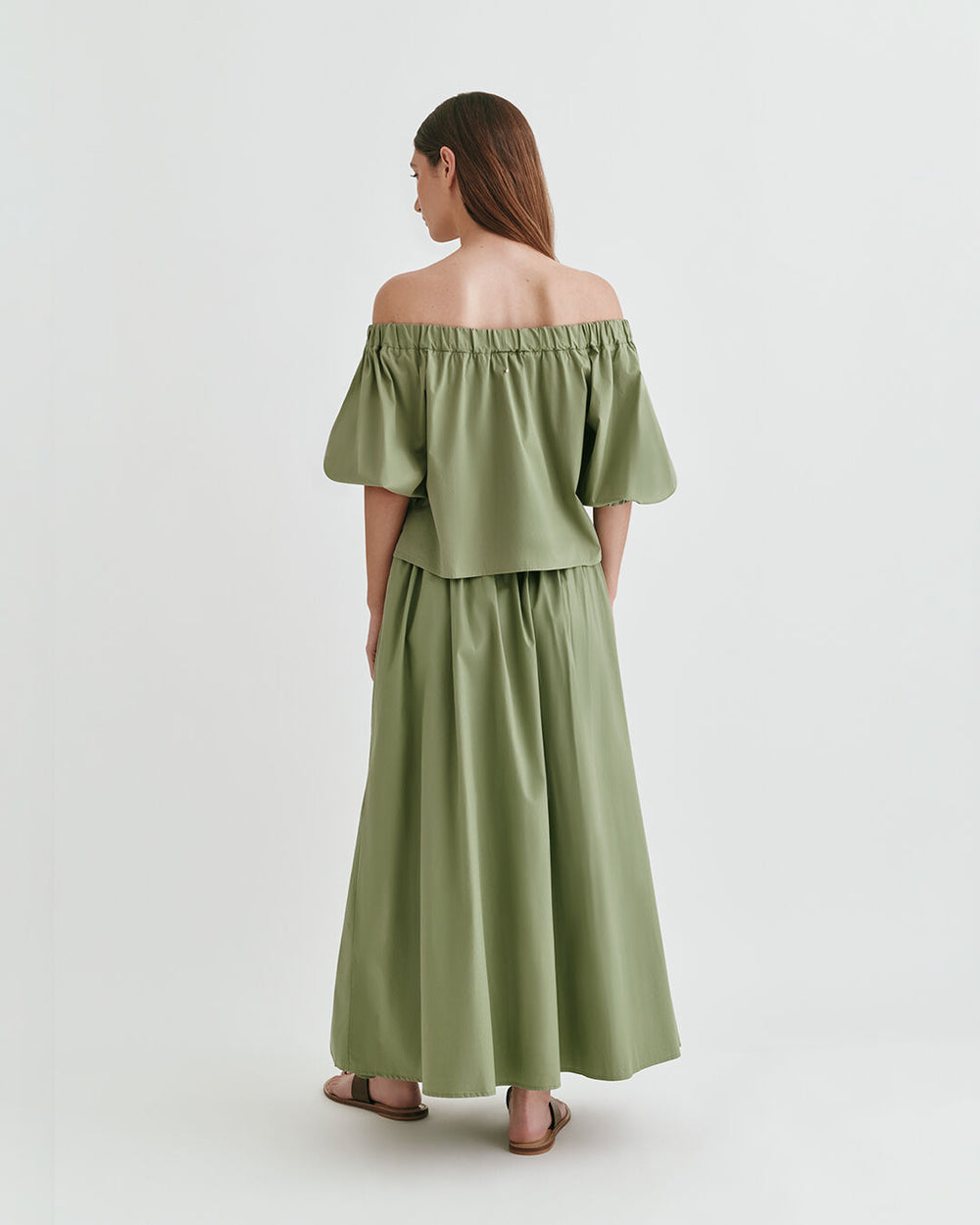 Woman standing in a long dress looking away from the camera