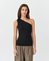 Woman in a one-shoulder top and pants standing straight.