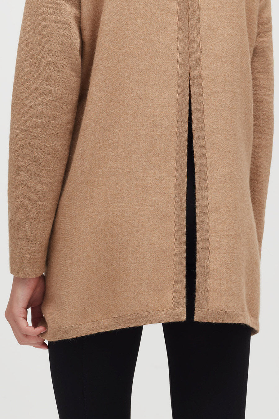 Close-up of a person wearing a coat and black pants.