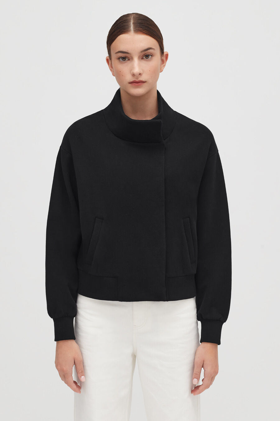 Woman in a jacket standing with her hands at her sides