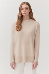 Woman standing in a sweater and pants, looking at the camera.