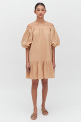 Woman standing in a puffy-sleeved off-shoulder dress with sandals.