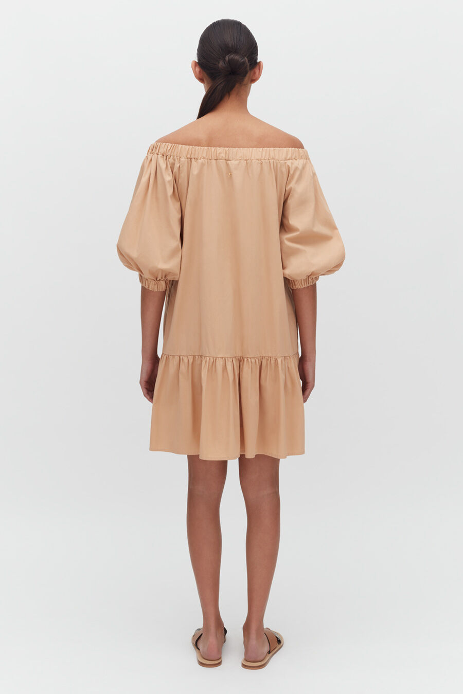 Woman in a dress standing with her back facing the camera.