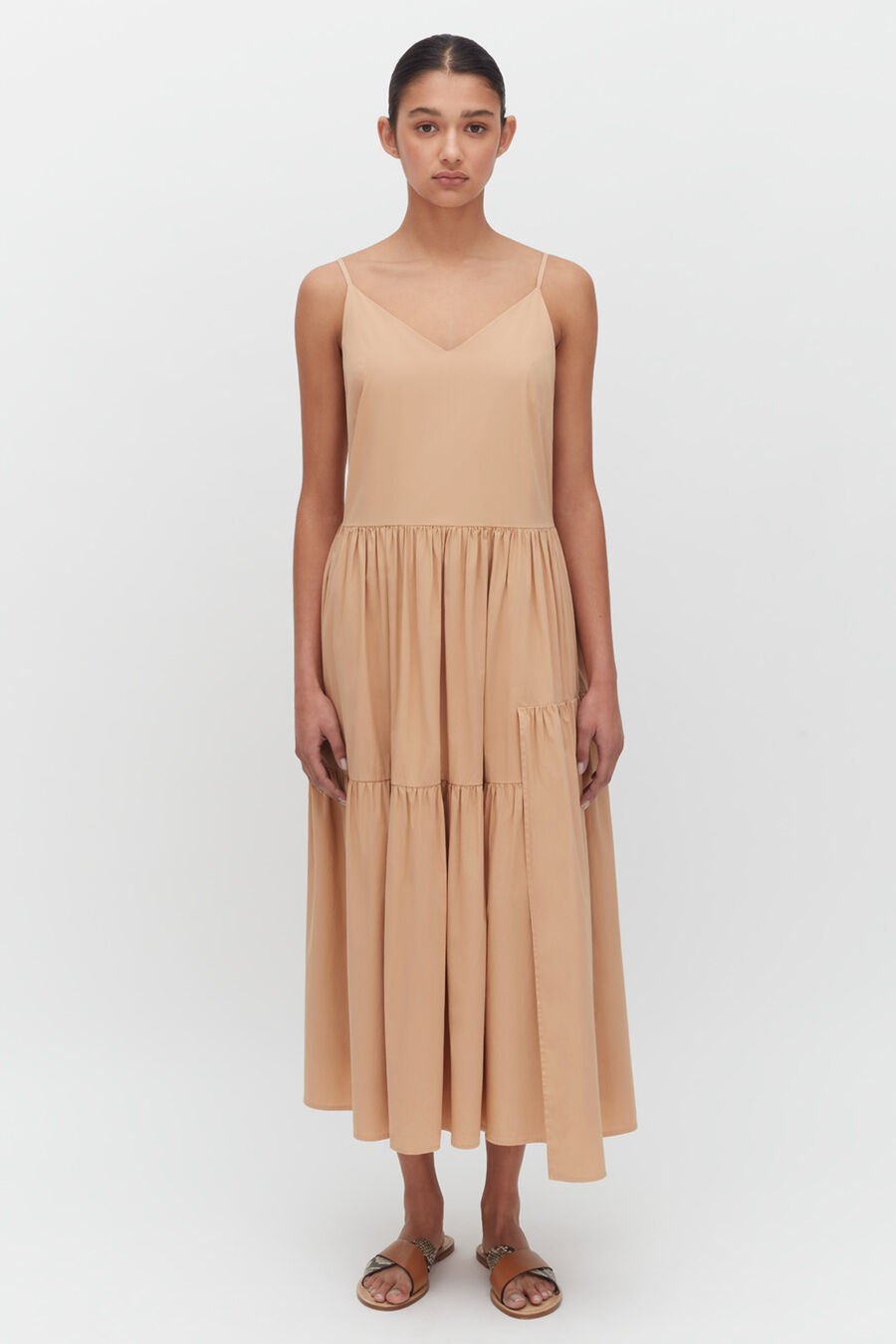 Woman wearing a sleeveless dress, standing against a plain background.