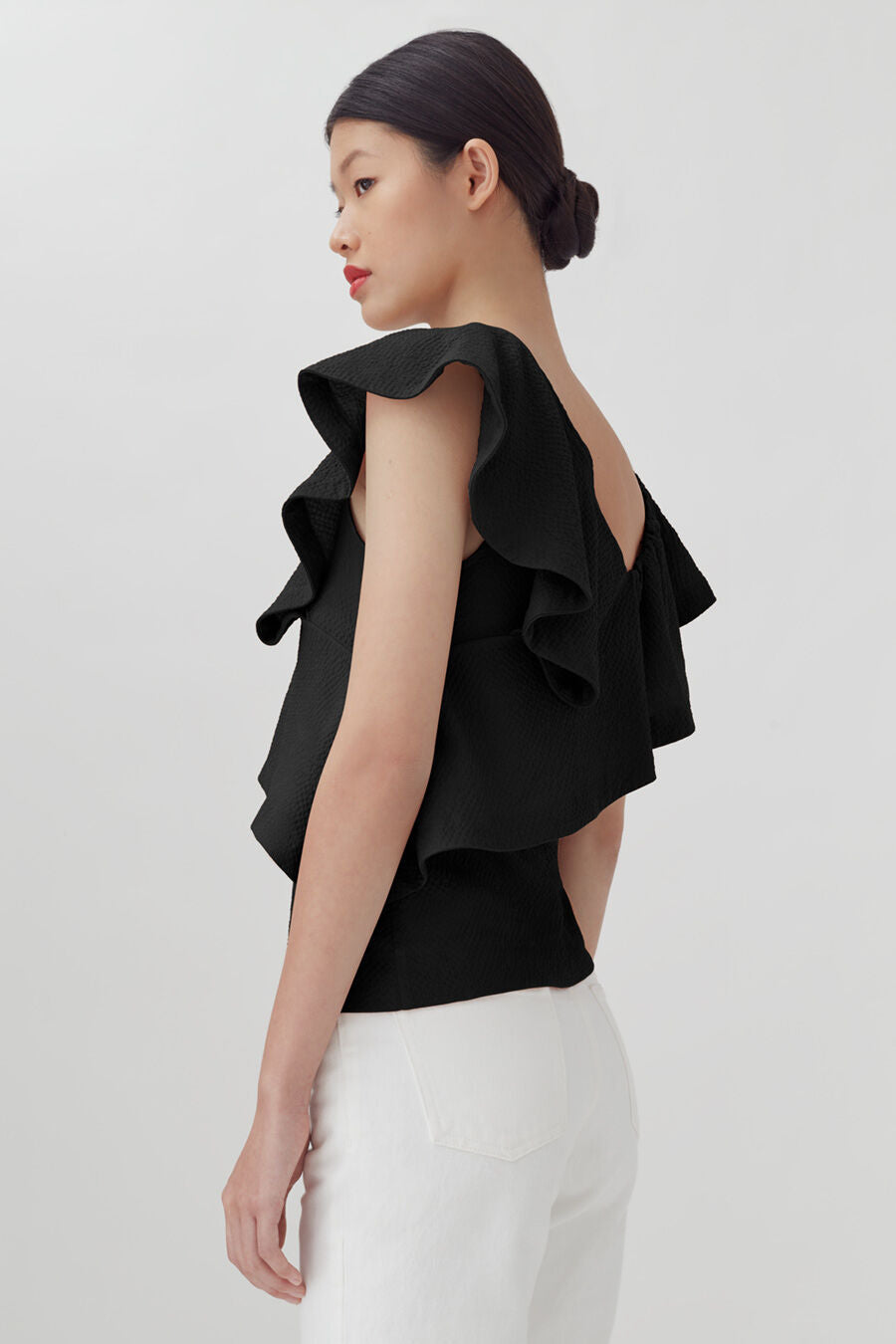 Woman in a layered top looking over her shoulder