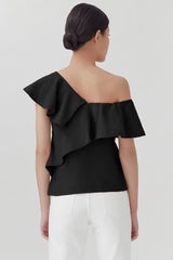 Woman from behind with a ruffled off-shoulder top and hair in a bun.