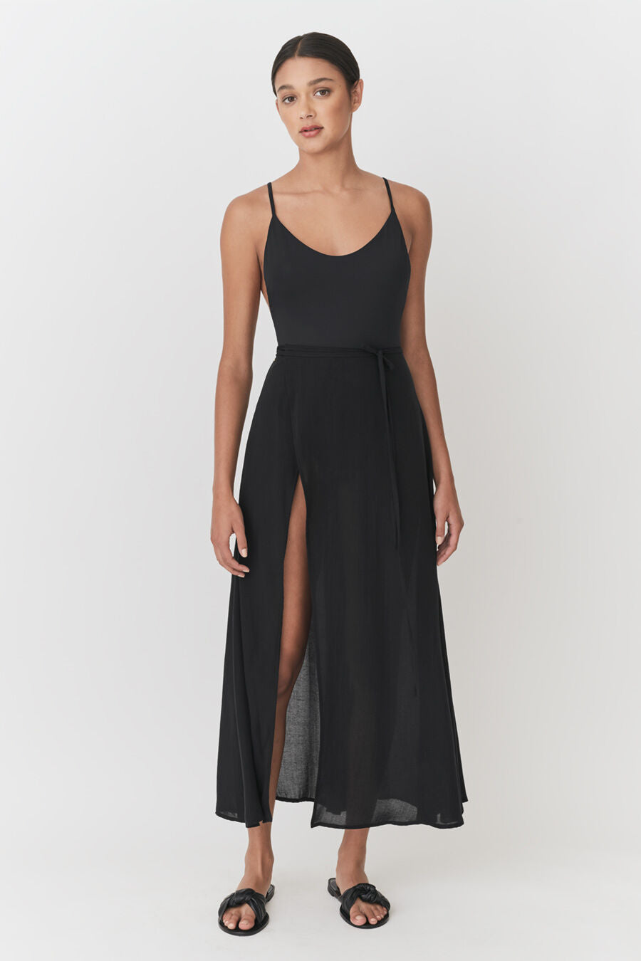 Woman in a long dress with a slit, standing and facing the camera.