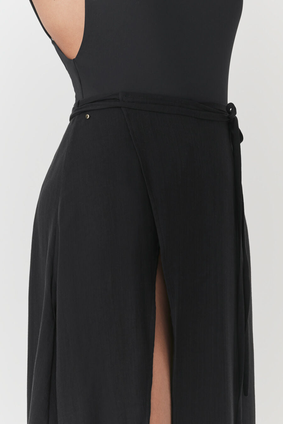 Person seen from the back wearing a fitted top and skirt with a slit.