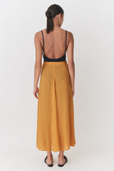 Woman viewed from behind wearing a tank top and long skirt, standing upright.