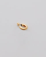 Earring in the shape of an abstract figure on a light background.