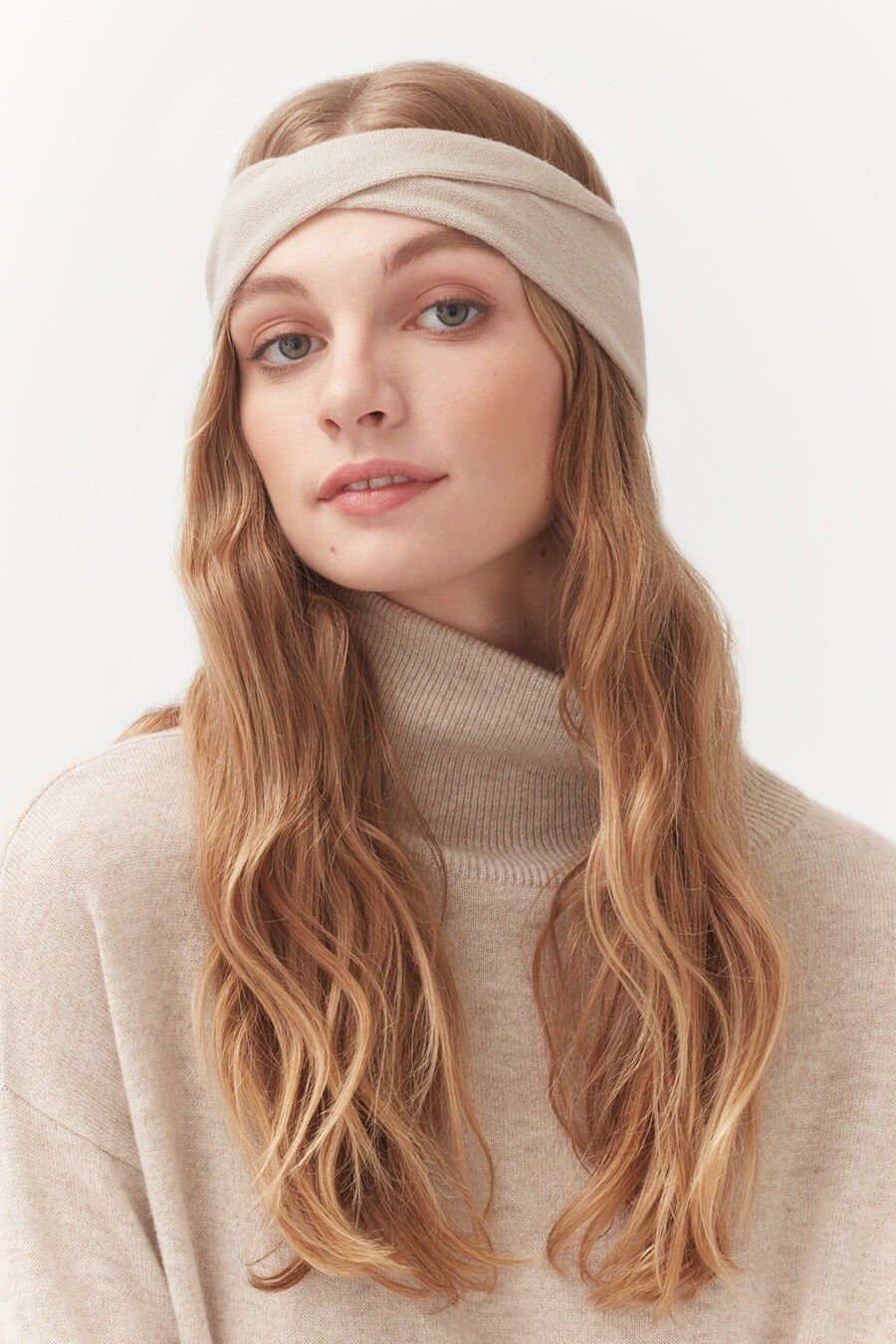 Woman with headband and turtleneck sweater looking at camera.
