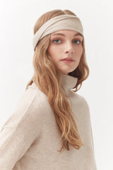 Woman wearing a headband and turtleneck sweater looking at camera.